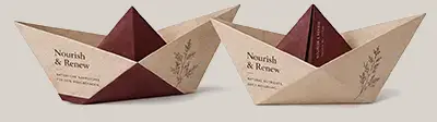 Zwei gefaltete Papierboote in Beige und Bordeaux